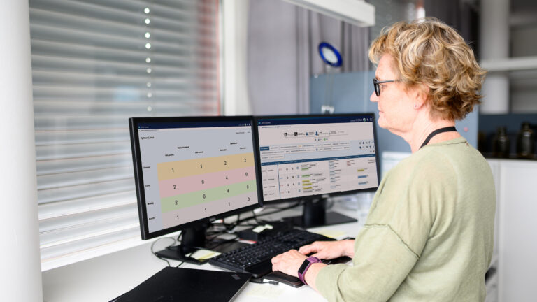 Employee at a service office with several digital whiteboards