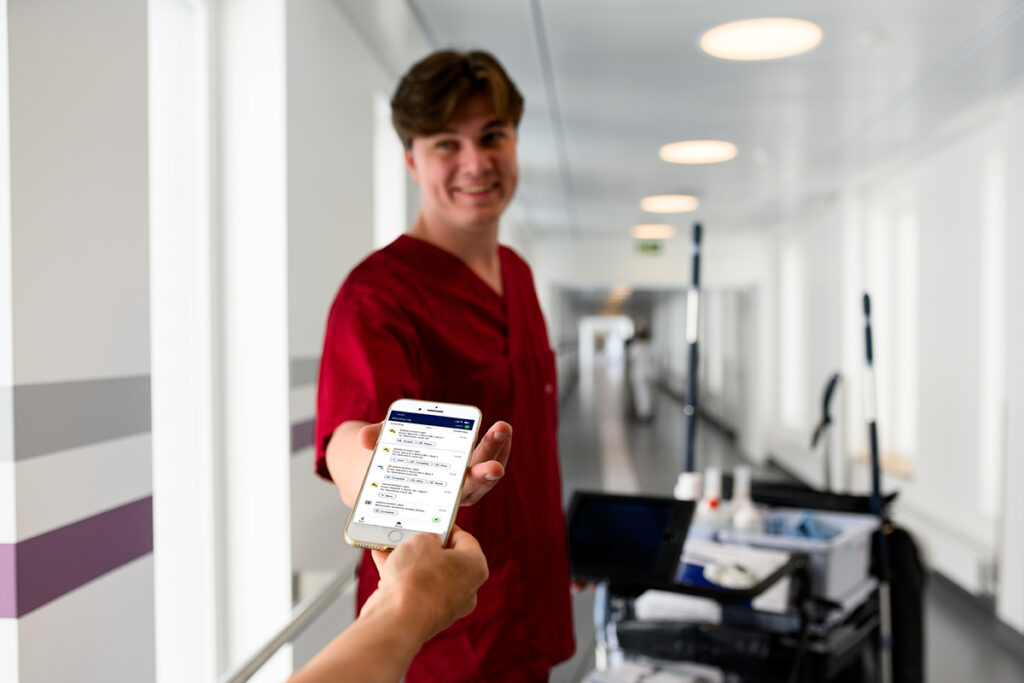 Member of hospital support staff receiving a task assignment on a mobile device using a real-time coordination system.