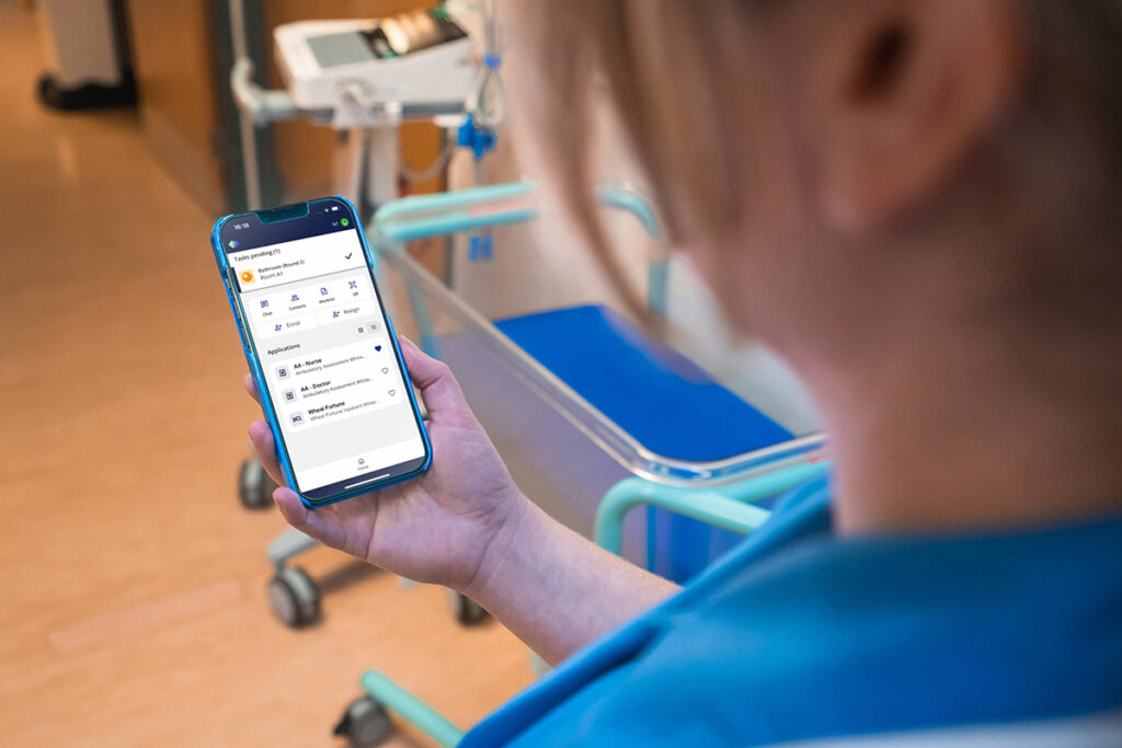 Nurse using a mobile healthcare application to receive tasks and patient information in a hospital ward.