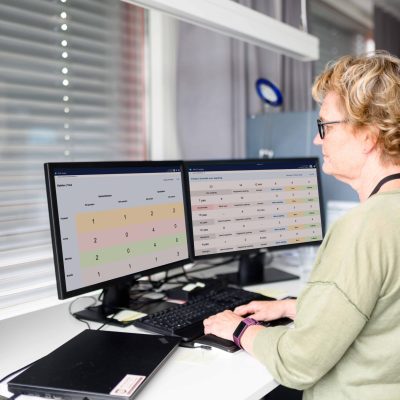 Employee at a service office with several digital whiteboards