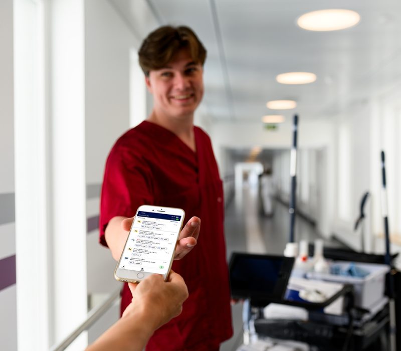 Member of hospital support staff receiving a task assignment on a mobile device using a real-time coordination system.